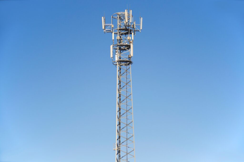 A tall cell tower set against a clear blue sky, representing modern communication technology.